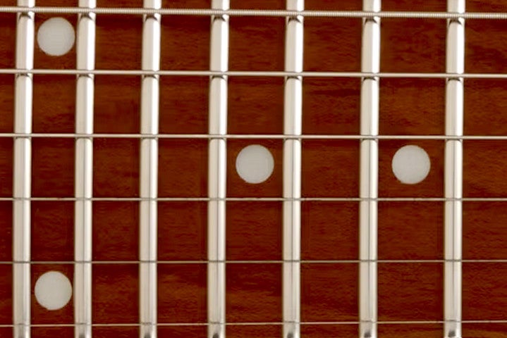 Close-up van stainless steel frets op een toets